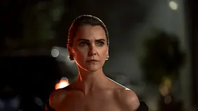 Keri Russell als Kate Wyler trägt ein schwarzes, schulterfreies Kleid und goldene Ohrringe. Sie blickt ernst zur Seite. - Foto: © 2026 Netflix, Inc.