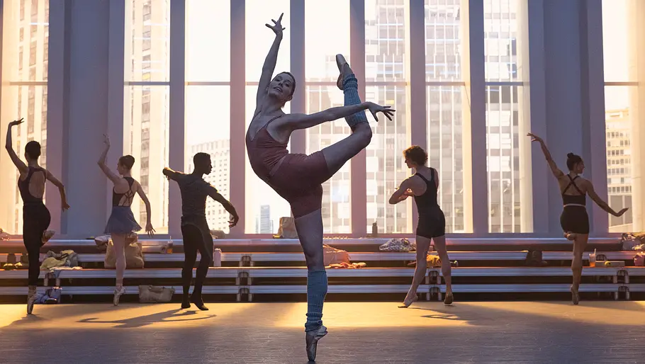 Für Ballettfans ist „Étoile“ ein Muss! Eine Balletttänzerin übt im Vordergrund eine Pose, weiter hinten stehen weitere Tänzerinnen und Tänzer.