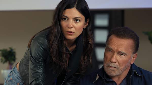 Luke sitzt, Emma beugt sich von der Seite leicht über ihn. Beide schauen nach vorne. - Foto: CHRISTOS KALOHORIDIS/NETFLIX
