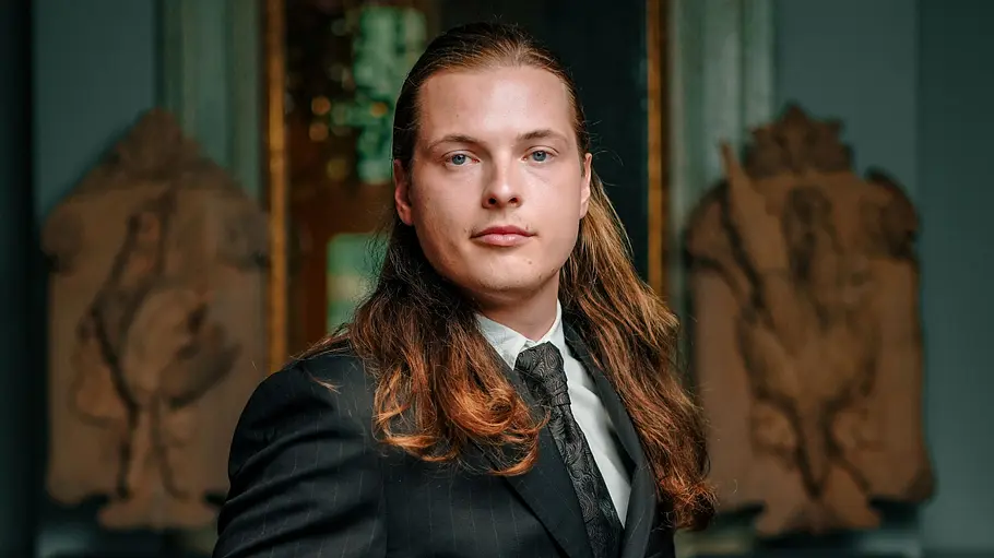 Gabriel Kelly ist Musiker. Gabriel Kelly mit langen, zurückgekämmten Haaren und ernstem Blick.