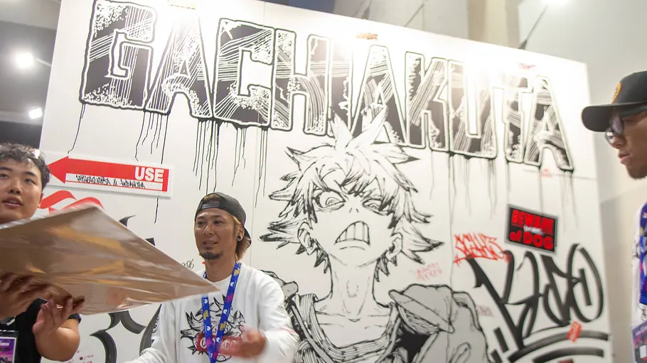 „Gachiakuta“-Graffiti-Designer Hideyoshi Andou auf der San Diego Comic-Con Hideyoshi Andou steht vor einer großen „Gachiakuta“-Graffitiwand mit einer gezeichneten Figur auf der San Diego Comic-Con 2026.