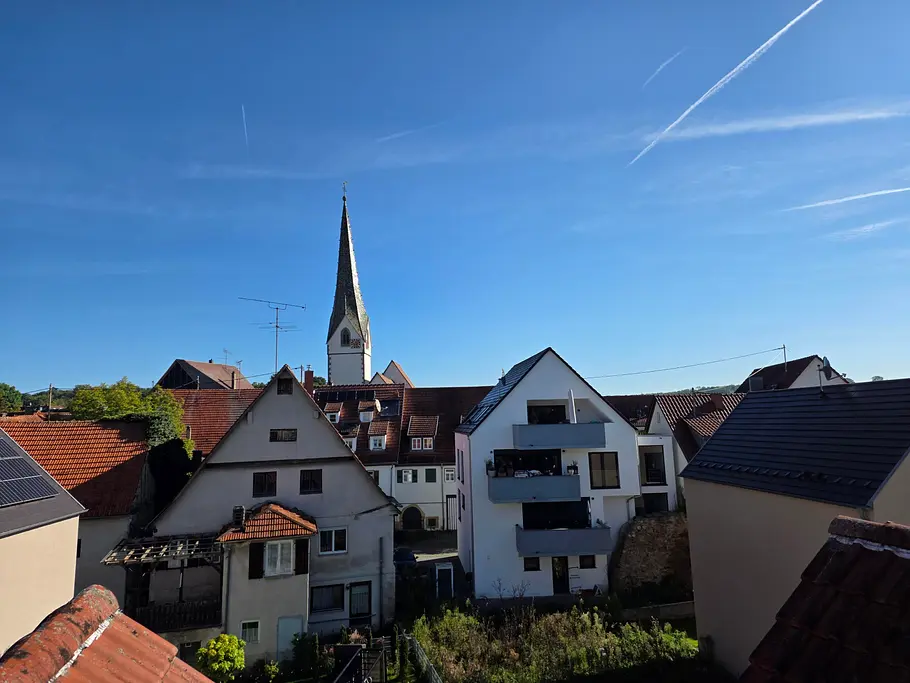 Ein Kirchturm aus der Ferne, davor ein paar Häuser
