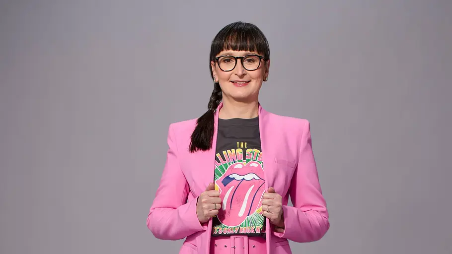 Annegret Schenkel trägt einen pinken Anzug und schaut siegessicher.