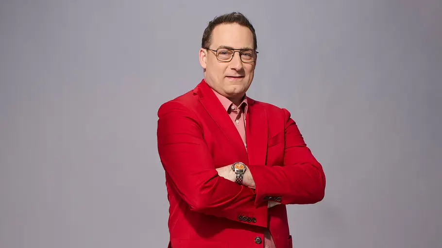Manuel Hobiger trägt einen roten Anzug. 