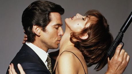 Pierce Brosnan als James Bond und Famke Janssen als Xenia Onatopp. Sie streckt ihren Kopf nach hinten, er küsst ihren Hals. - Foto: TMDB