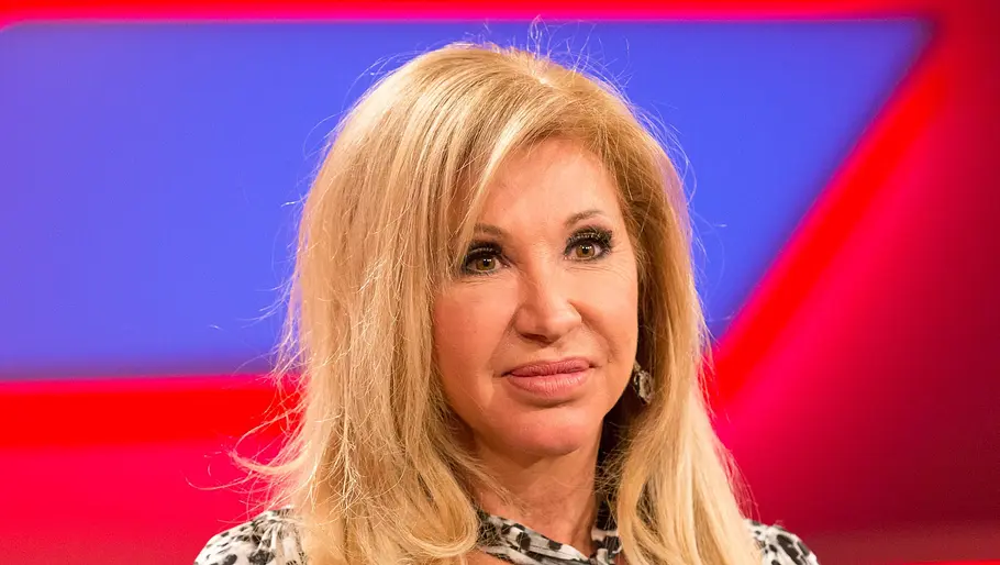 Carmen Geiss traumatisiert von Überfall Carmen Geiss schaut ernst nach vorne. Sie trägt eine Leo-Bluse und sitzt vor einem rot-blauen Hintergrund.