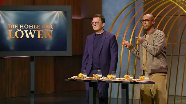 David Weyhe und Amiaz Habtu stehen hinter einem Tisch mit Speisen und Gläsern neben dem Bildschirm „Die Höhle der Löwen“. - Foto: RTL David Weyhe und Amiaz Habtu stehen hinter einem Tisch mit Speisen und Gläsern neben dem Bildschirm „Die Höhle der Löwen“. - Foto: RTL