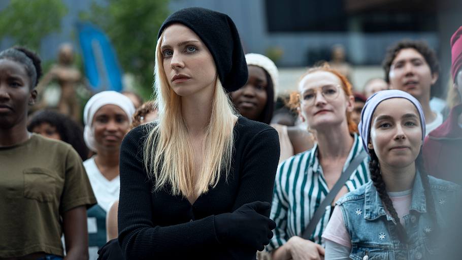 Maddie Phillips, die in Gen V Kate spielt, steht inmitten einer Menge anderer Supes. Sie trägt einen schwarzen Pullover und eine schwarze Mütze und wirkt sichtlich zerrüttet.
