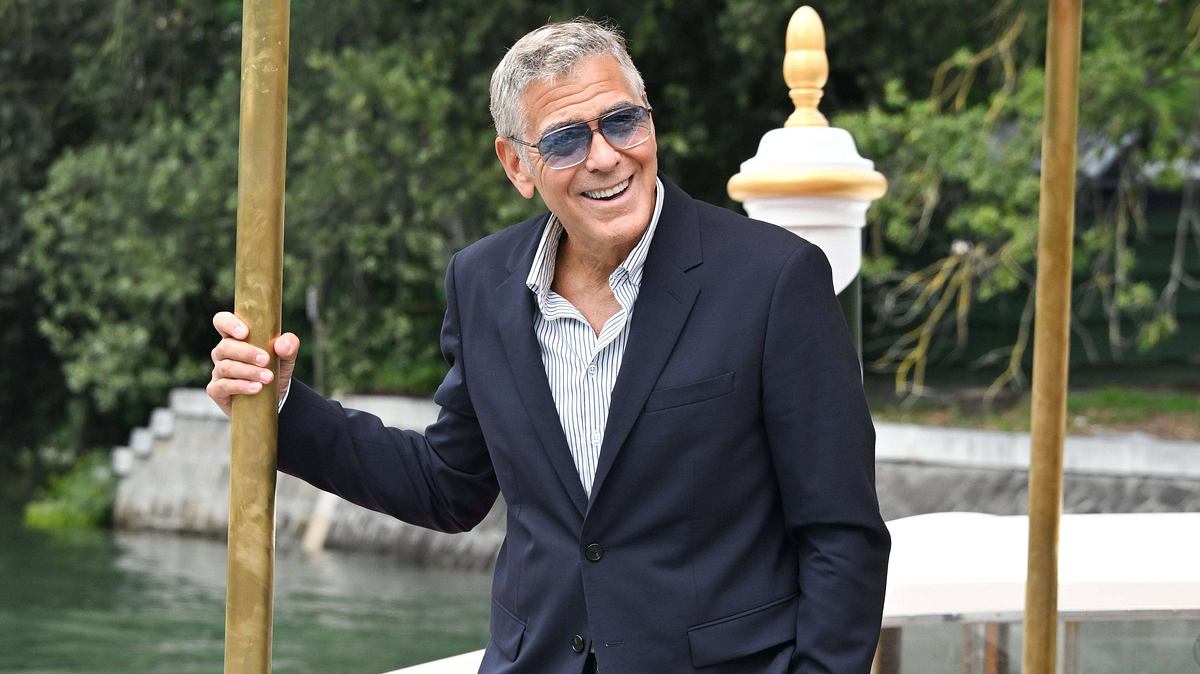George Clooney krank George Clooney hält sich erschöpft, aber lachend an einer Stange fest!