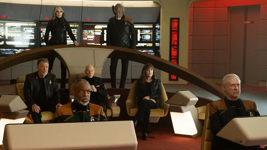 Gerade Staffel 3 von „Picard“ machte Fanträume wahr. Sieben Personen in dunklen Uniformen sitzen und stehen auf einer Raumschiffbrücke mit beleuchteten Bildschirmen und Pulten.