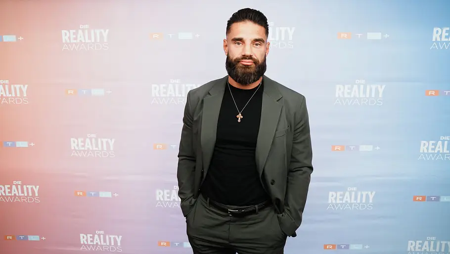 Aleks Petrovic bei den Reality Awards Aleks im grünen Anzug posiert vor der „Die Reality Awards“-Fotowand.