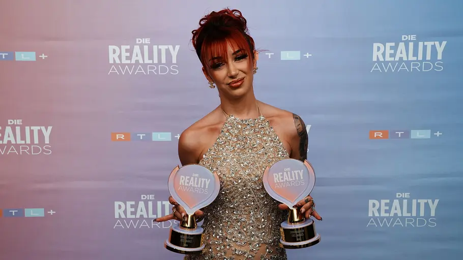 Ariel bei den Reality Awards Ariel mit rotem Haar hält zwei Trophäen der „Die Reality Awards“ in den Händen.