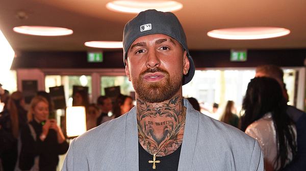 Gigi Birofio posiert mit umgedrehter Cap und grauem Blazer für die Kamera. - Foto: IMAGO / Gartner