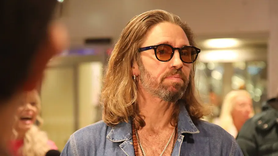 Gil Ofarim mit ernstem Blick und Brille am Flughafen.