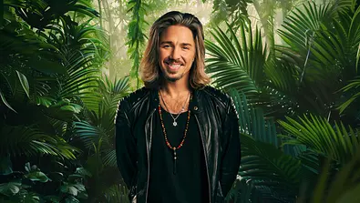 Gil Ofarim lächelt vor einem Dschungel-Hintergrund. - Foto: RTL