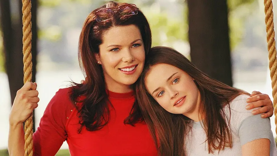 Gilmore Girls Alexis Biedel und Lauren Graham sitzen lächelnd auf einer Schaukel.
