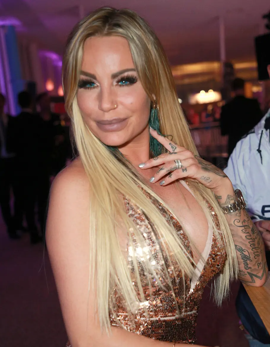 Gina-Lisa Lohfink 2018 Gina-Lisa im goldenen Paillettenkleid sitzt an einem Tisch bei einer Abendveranstaltung; Gäste im Hintergrund.