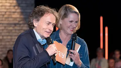 Giovanni di Lorenzo und Judith Rakers stehen mit Mikrofonen und Moderationskarten im „3nach9“-Studio. - Foto: IMAGO / Stefan Schmidbauer