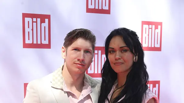 Giovanni Weisheit steht gemeinsam mit Vanessa Neigert vor einer Pressewand und blickt in die Kamera. - Foto: IMAGO / Matthias Wehnert Giovanni Weisheit steht gemeinsam mit Vanessa Neigert vor einer Pressewand und blickt in die Kamera. - Foto: IMAGO / Matthias Wehnert