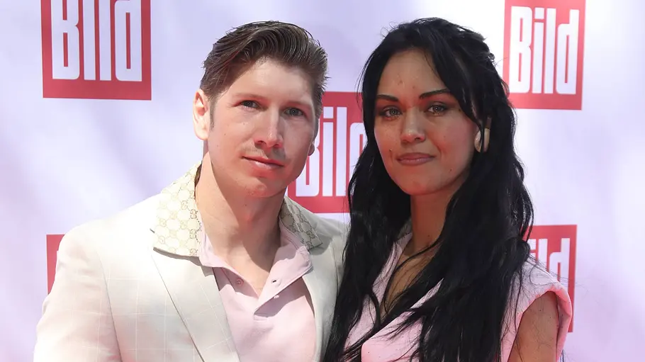 Giovanni Weisheit mit Vanessa Neigert Giovanni Weisheit steht gemeinsam mit Vanessa Neigert vor einer Pressewand und blickt in die Kamera.