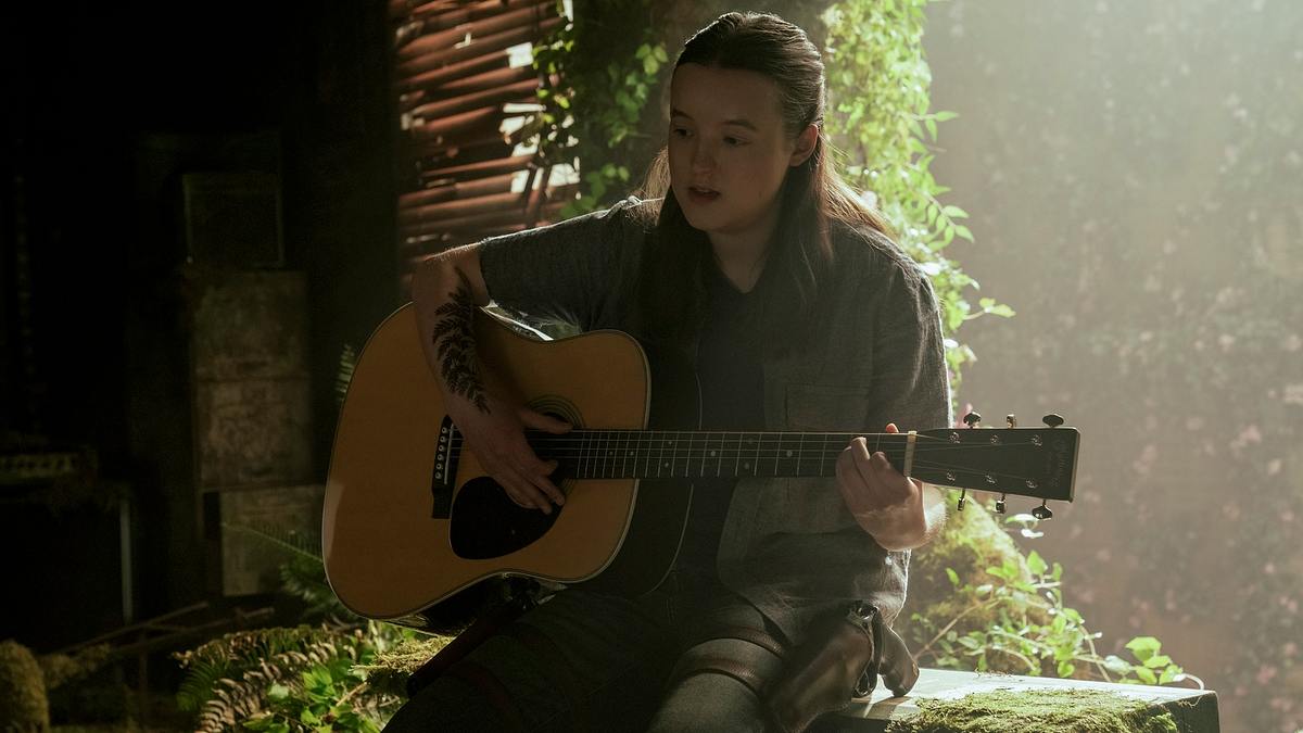 Gitarren verbindet Ellie stets mit der Erinnerung an Joel. Ellie sitzt auf einer Kiste und spielt auf einer Gitarre.