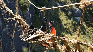 Giulia Siegel hängt in hunderten Metern höhe zwischen zwei Felsen, gesichert durch ein Seil. Die Herausforderungen von The Summit haben es in sich.  - Foto: Amazon Prime
