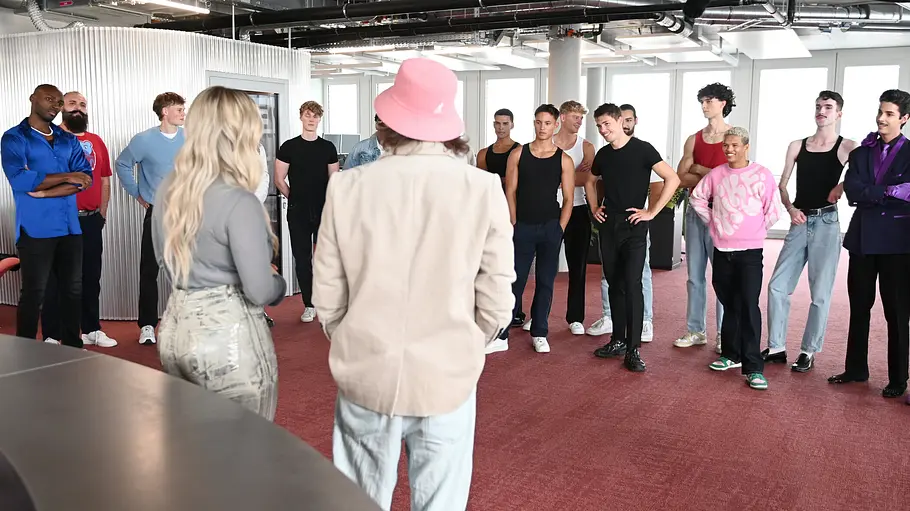 Beatrice Egli vor einer Gruppe männlicher Kandidaten in einem hellen Raum während einer Challenge-Besprechung.
