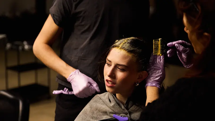 Antonia sitzt im Friseurstuhl und bekommt gelbe Farbe aufs Haar aufgetragen.