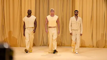 Drei Models laufen synchron über einen gelb inszenierten Runway und präsentieren monochrome Looks in verschiedenen Gelbtönen vor passendem Vorhang. - Foto: ProSieben/Daniel Graf