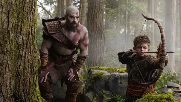 Kratos steht neben seinem Sohn und schaut ihm zu, wie er den Bogen spannt. - Foto: TMDB Kratos steht neben seinem Sohn und schaut ihm zu, wie er den Bogen spannt. - Foto: TMDB