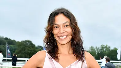 Gisele Oppermann mit offenen Haaren und in einem Satinkleid. Sie lächelt draußen breit in die Kamera. - Foto: IMAGO / Future Image