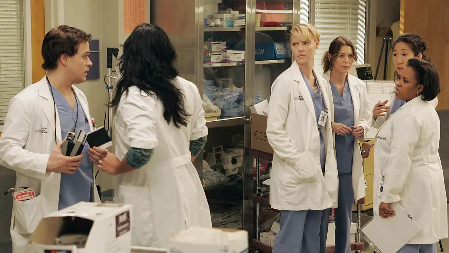 Greys Anatomy Mehrere Ärztinnen und Ärzte stehen im Stationszimmer eines Krankenhauses zusammen und führen ein ernstes Gespräch. Die Szene stammt aus der Krankenhausserie „Grey’s Anatomy“.