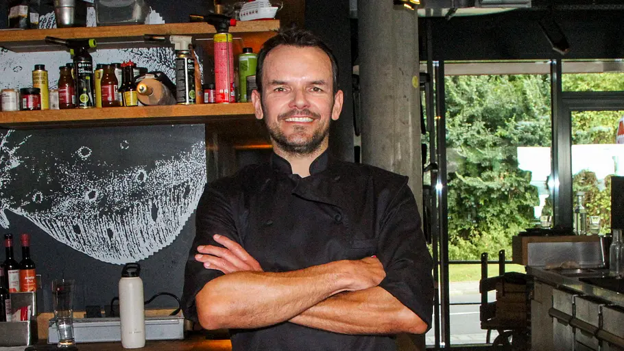 Szeffen Henssler steht in einer Küche und verschränkt breit lächelnd die Arme vor seinem Körper. Szeffen Henssler steht in einer Küche und verschränkt breit lächelnd die Arme vor seinem Körper.