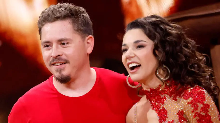 Gustav Schäfer mit Tanzpartnerin Anastasia Maruster bei „Let’s Dance“ Gustav Schäfer und seine Tanzpartnerin Anastasia Maruster stehen lachend nebeneinander auf dem „Let’s Dance“-Parkett in roten Outfits