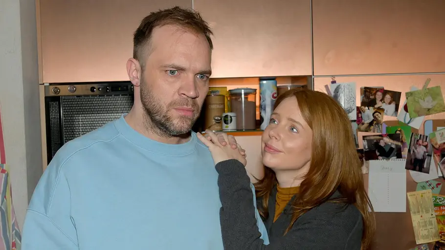 Erik schaut ernst, während Toni zu ihr aufblickt.