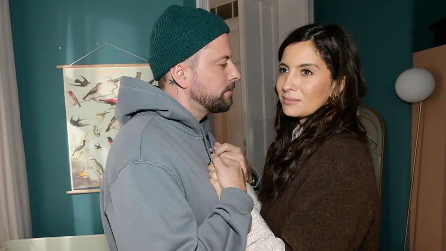 John hält Lauras Hände, während er sie verliebt anblickt.