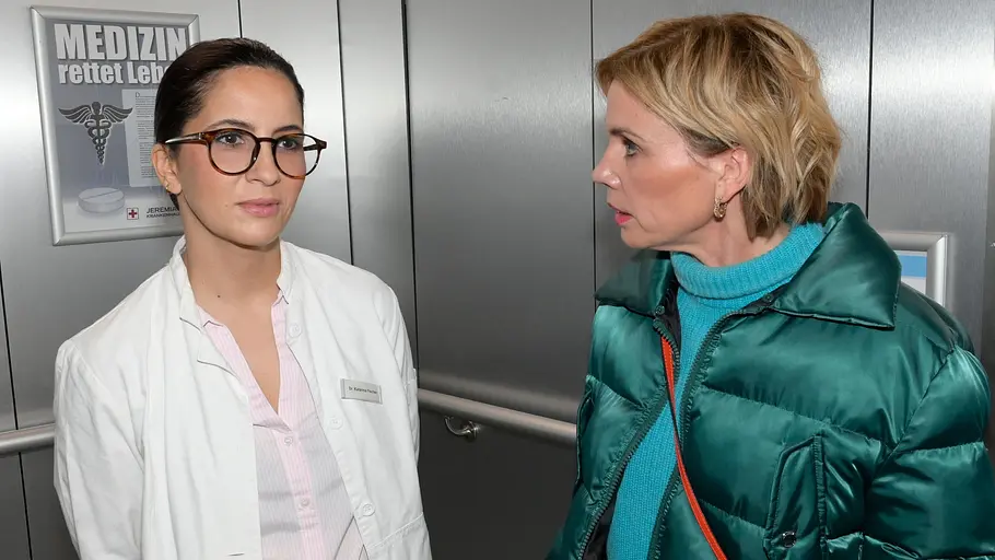 Laura will sich an Hardenberg heranschleichen. Laura schaut ernst mit Brille, während Yvonne sie entsetzt anschaut.