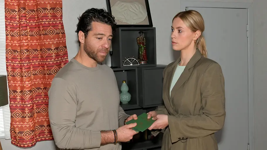 GZSZ Zoe und Carlos Zoe zeigt Carlos entschlossen die gefälschten Pässe. Er schaut traurig zur Seite.