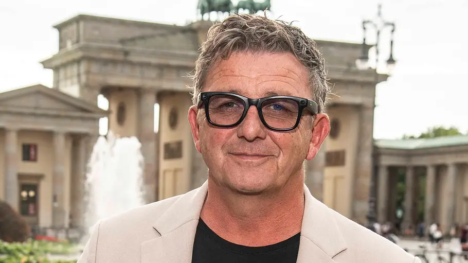 Hans Sigl Hans Sigl steht vor dem Brandenburger Tor mit Sonnenbrille und lächelt.