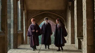 Ron Weasley (l.), Harry Potter (m.) und Hermine Granger (r.) laufen durch die Korridore Hogwarts. - Foto: Courtesy of HBO