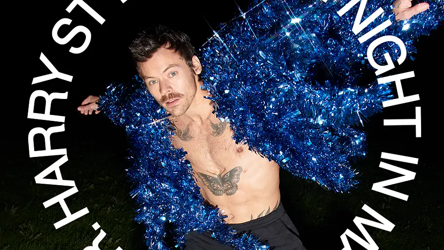 Harry Styles Promobild zu „Harry Styles: One Night in Manchester“: Harry Styles springt in einer funkelnden blauen Jacke vor schwarzem Hintergrund, umgeben vom kreisförmigen Schriftzug des Konzertfilms, der auf Netflix erscheint.