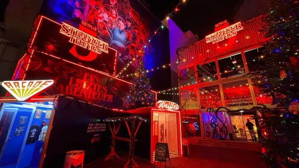 Der Hawkins Christmas Market öffnet seine Pforten: Zu sehen ist der Eingang zur Arcade, der Demogorgon-Waffel-Stand und die Starcourt Mall. - Foto: © Agentur XY GmbH