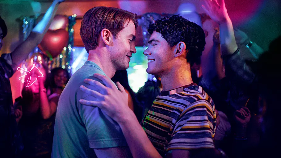 Charlie und Nick tanzen auf einer Party und lächeln einander an.