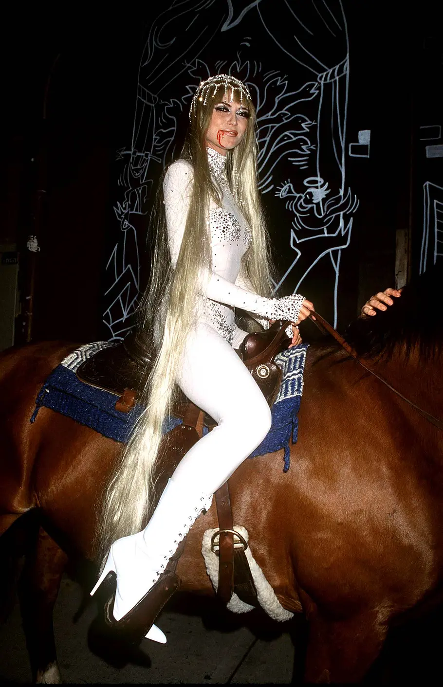 Heidi Klum zu Halloween 2001 als Lady Godiva Heidi Klum saß an Halloween 2001 im weißen Glitzerkostüm mit sehr langen blonden Haaren und rotem Kunstblut am Mund auf einem braunen Pferd.