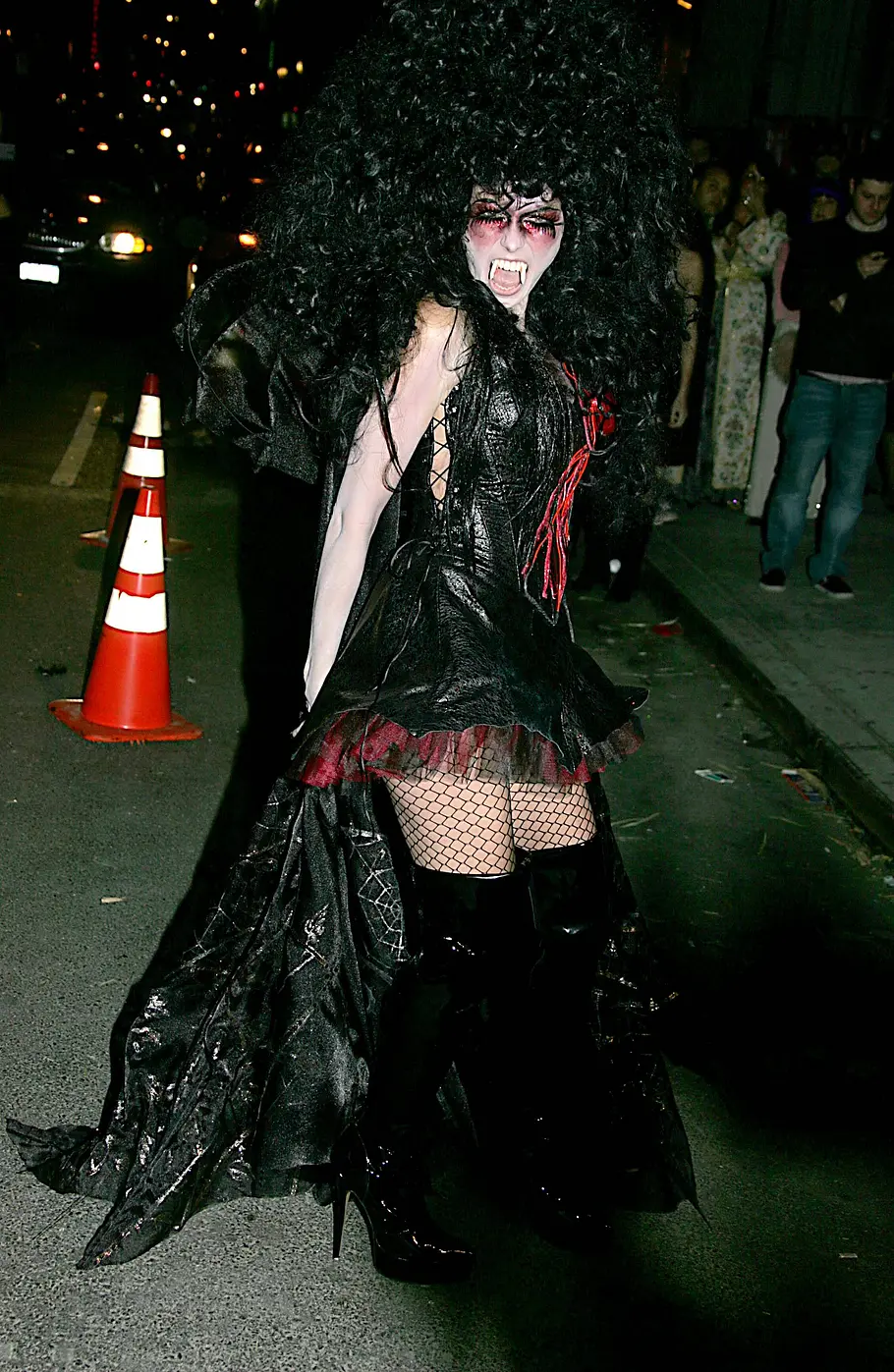 Heidi Klum zu Halloween 2005 als Vampir Heidi Klum trug zu Halloween 2005 ein schwarzes Vampirkostüm mit Fangzähnen, üppiger Lockenperücke, Netzstrümpfen und hohen Lackstiefeln.