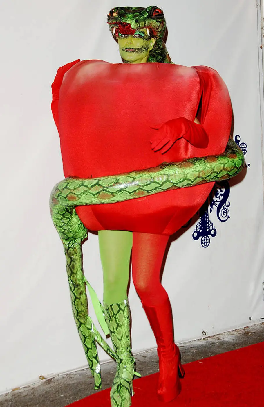 Heidi Klum zu Halloween 2006 als Sündenfall (Apfel und Schlange) Heidi Klum trug zu Halloween 2006 ein rotes Apfelkostüm mit einer großen grünen Schlange um den Körper und einem Schlangenkopf über dem Gesicht.