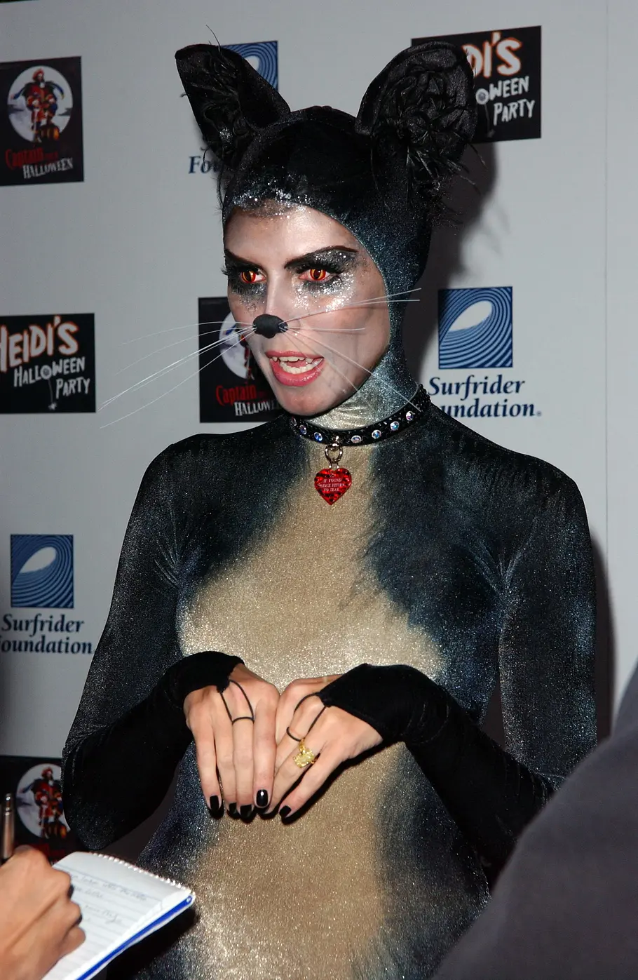 Heidi Klum zu Halloween 2007 als Katze Heidi Klum trug zu Halloween 2007 ein glitzerndes Katzenkostüm mit großen Ohren, Schnurrhaaren, orangefarbenen Augen und einem Halsband.