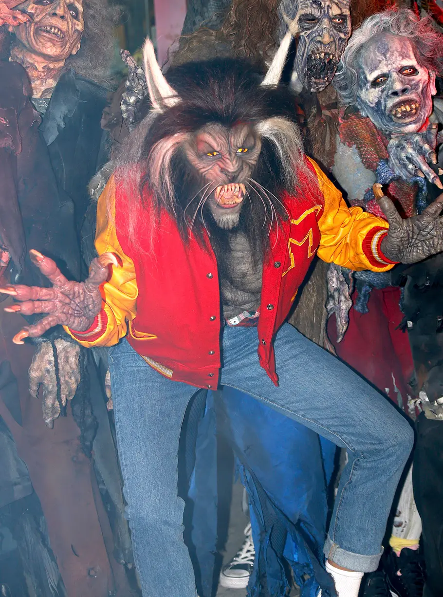 Heidi Klum zu Halloween 2017 als Thriller-Werwolf Heidi Klum posiert an Halloween 2017 im Werwolfkostüm mit rot-gelber Collegejacke und Jeans zwischen mehreren Menschen in Zombiekostümen.