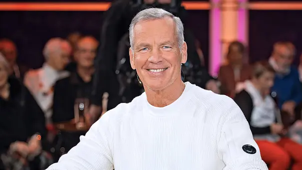 Henry Maske sitzt lächelnd in weißem Pullover und Jeans in einem braunen Sessel. Im Hintergrund sitzt Publikum. - Foto: IMAGO / STAR-MEDIA Henry Maske sitzt lächelnd in weißem Pullover und Jeans in einem braunen Sessel. Im Hintergrund sitzt Publikum. - Foto: IMAGO / STAR-MEDIA