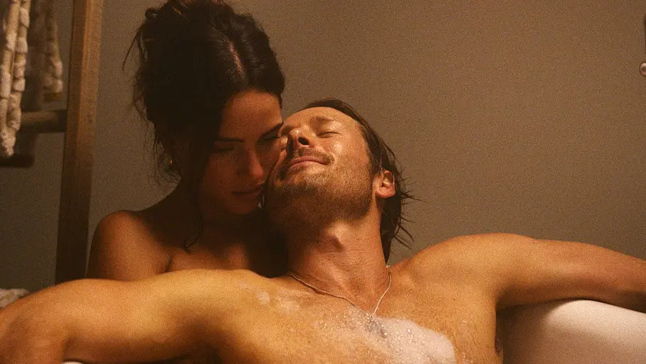 Hit Man Glen Powell liegt mit Adria Arjona in der Badewanne.